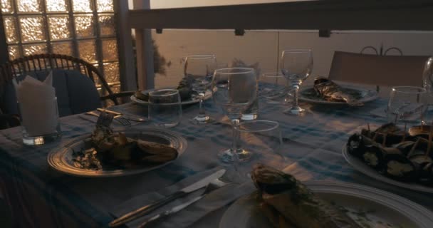 Ao pôr do sol na cidade de Perea, Grécia, mesa de jantar servida com peixe cozido — Vídeo de Stock