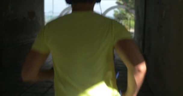 Young man in headphones runs through alley of city Perea, Greece — Wideo stockowe