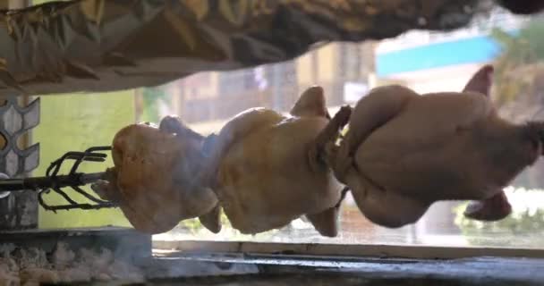 Parrilla de pollo girando en un pincho en la cafetería contra la ventana de visualización — Vídeos de Stock