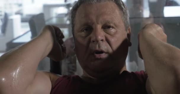 Starszy mężczyzna trenuje ciężko w siłowni, ma ciężki oddech i pot na całym ciele — Wideo stockowe