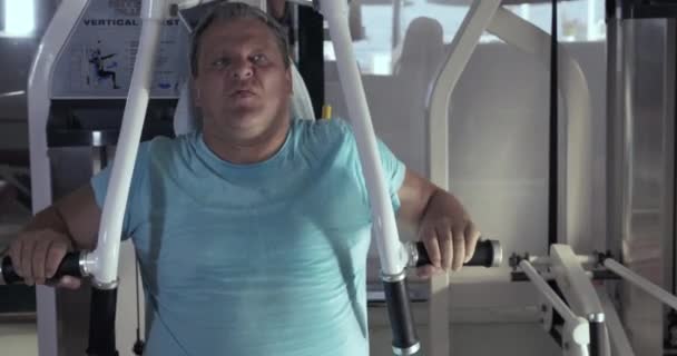 Крупный план взрослого мужчины в тренажерном зале выполняет упражнения грудной пресс — стоковое видео