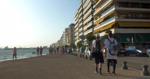 Två unga pojkar promenad längs havet i Thessaloniki, Grekland — Stockvideo