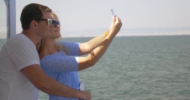 На море в городе Перея, Греция на корабле молодая пара делает селфи на мобильном телефоне — стоковое видео