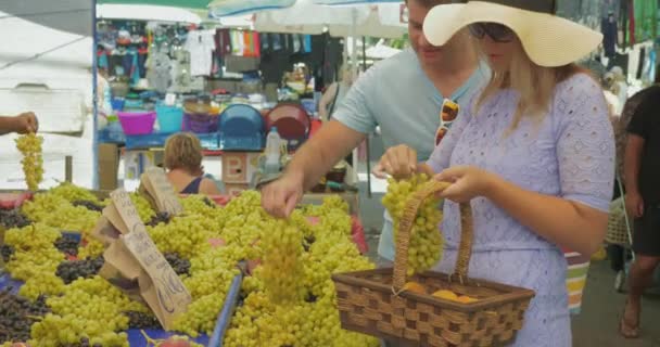 ブドウを選び、屋外市場で笑顔で話すカップル。テッサロニキ(ギリシャ) — ストック動画