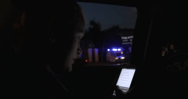 Jovem mulher usando celular durante passeio de carro noturno na cidade — Vídeo de Stock