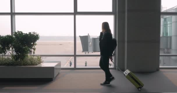 Женский чат на мобильном телефоне в терминале аэропорта — стоковое видео