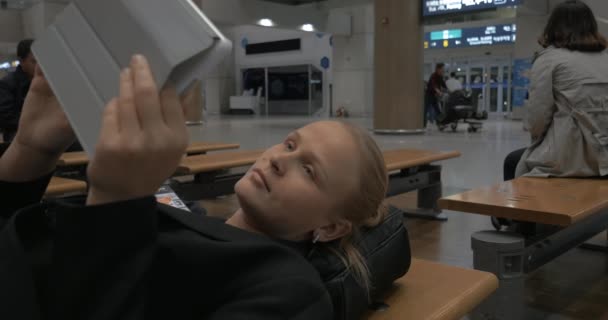 Mujer con almohadilla acostada en el banco en la terminal del aeropuerto — Vídeo de stock