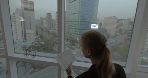 Mujer trabajando por negocios con almohadilla por ventana con vista a Seúl, Corea del Sur — Vídeo de stock