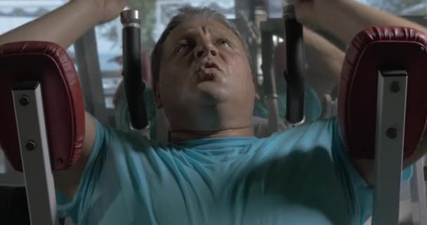 Homem crescido em camisa azul no ginásio realizando exercícios nos abdominais superiores — Vídeo de Stock