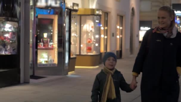 In Wenen, Oostenrijk in de avond op vierkant wandelen een jonge moeder en holding hand van een kleine zoon — Stockvideo