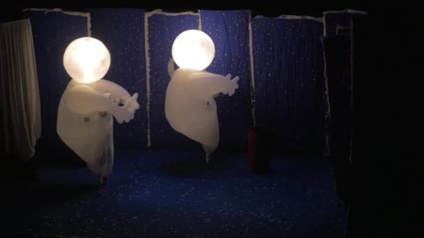Nello spettacolo sulla neve di Slava Polunin due persone in costume con teste luminose attraversano il palco e spengono la luce nelle teste — Video Stock