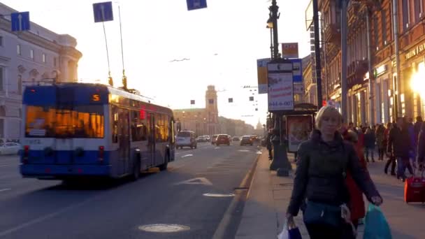 Al atardecer en la acera caminando personas, en una carretera concurrida conducir coches y autobuses — Vídeos de Stock