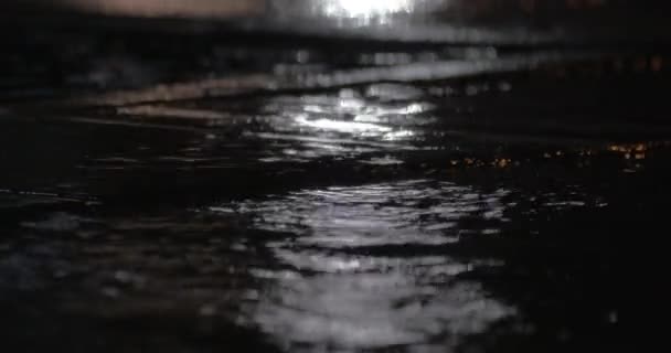 Βροχή λακκούβες και υπάγονται σταγόνες εναντίον αυτοκινήτων φώτα της πόλης — Αρχείο Βίντεο