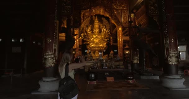 Женщина фотографирует статую в буддийском храме Бай Динь, Вьетнам — стоковое видео