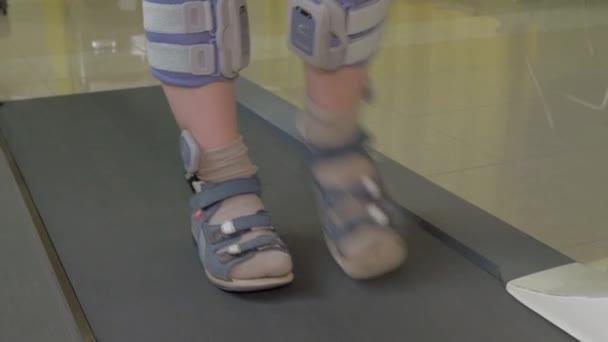 Vista de cerca de los pies de niño pequeño en la cinta de correr en el vendaje ortopédico especial y desgaste del pie — Vídeo de stock