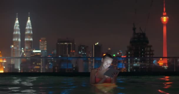 Mulher com almofada na piscina do último piso da noite Kuala Lumpur — Vídeo de Stock