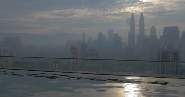 Vista d'onda su acqua su primo piano e paesaggio urbano in nebbia su cielo nuvoloso e luce del sole. Kuala Lumpur, Malesia — Video Stock