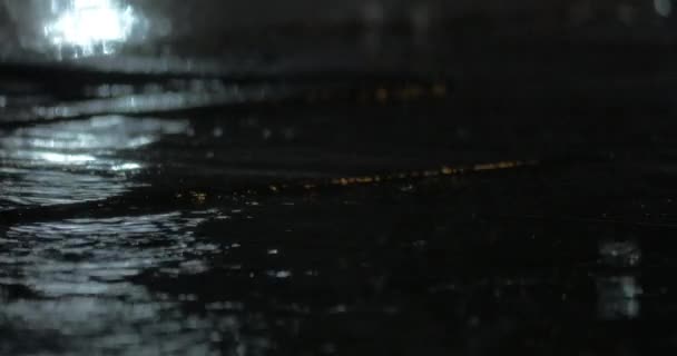 Дождь и лужи на тротуаре ночью — стоковое видео