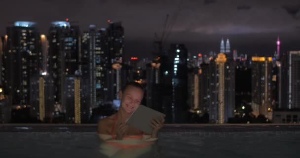 W basenie na dachu hotelu w Kuala Lumpur, Malezja kobieta działa na tablecie — Wideo stockowe