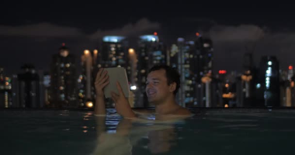Homem com almofada na piscina do telhado da noite Kuala Lumpur — Vídeo de Stock