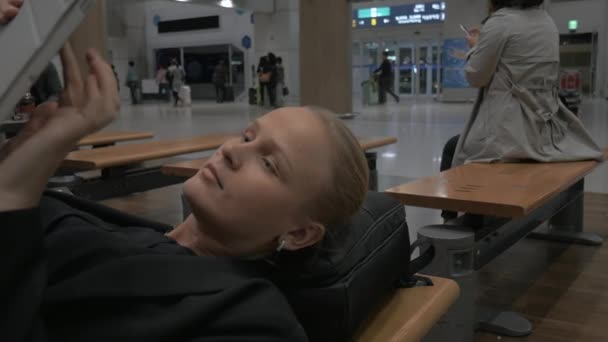 Frau wartet im Flughafen auf Bank liegend mit Polster — Stockvideo