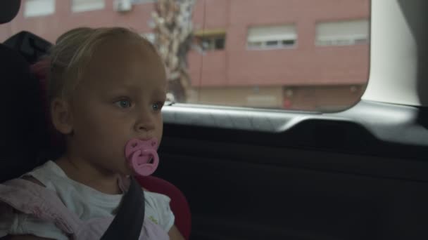 Toddler girl with pacifier traveling by car. Safe ride in child seat — Stock Video