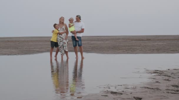 Οικογενειακό πορτραίτο στην παραλία. Γονείς με δύο υπέροχα παιδιά. — Αρχείο Βίντεο