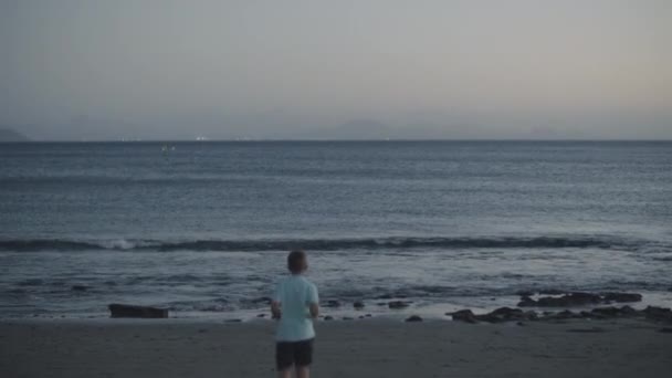 Child throwing stones into the ocean. Black sand beaches of Canary Islands — Stock Video