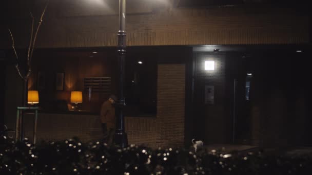Uomo anziano che cammina con un cane sotto pioggia gocciolante la sera — Video Stock