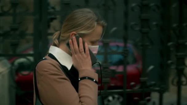 Mujer enmascarada hablando en móvil al caminar por la ciudad — Vídeos de Stock