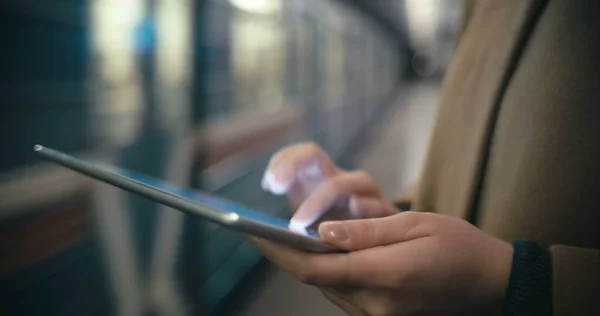 Woman using tablet PC by the leaving train in subway — Stock Photo, Image