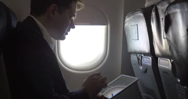 Jonge zakenman werkt met pad in het vliegtuig — Stockfoto
