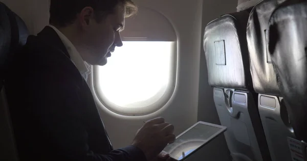 Young businessman working with pad in plane — Stock Photo, Image