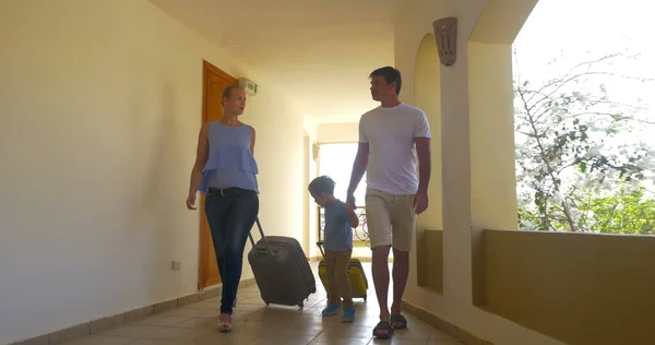 Família com sacos rolantes no corredor do hotel — Fotografia de Stock