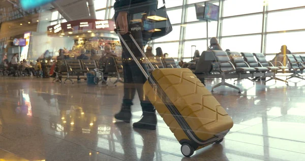 Woman with trolley bag walking slowly in lounge — Stock Photo, Image