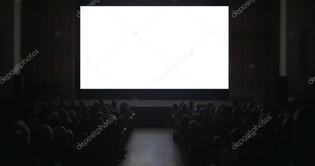 Viewers in dark cinema hall with blank screen