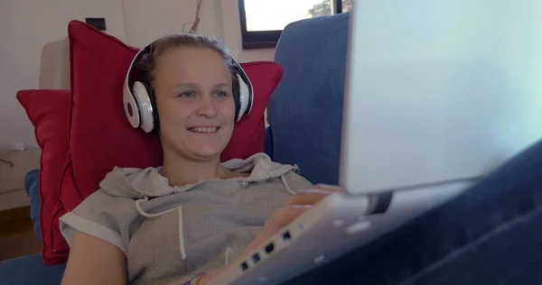 Kobieta w słuchawkach z laptopem na kanapie — Zdjęcie stockowe
