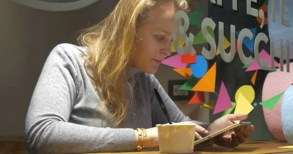 Mujer en la cafetería comiendo helado y usando almohadilla —  Fotos de Stock