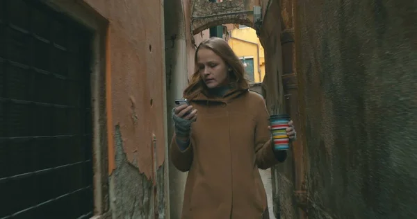 ヴェネツィアを歩く電話とコーヒーを持つ女性 — ストック写真