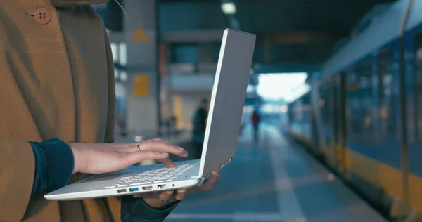 Menina trabalhando com laptop na estação ferroviária — Fotografia de Stock