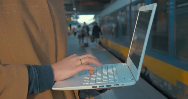Woman using laptop by train at the station