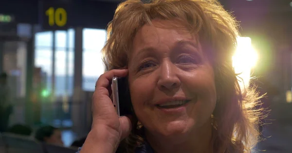 Mujer mayor teniendo una charla telefónica vívida en el aeropuerto — Foto de Stock