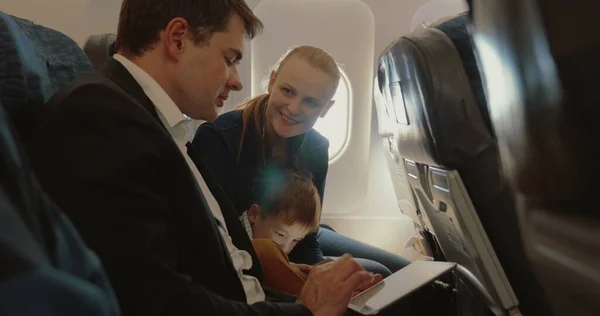 Busy father, child and mother traveling by plane — Stock Photo, Image