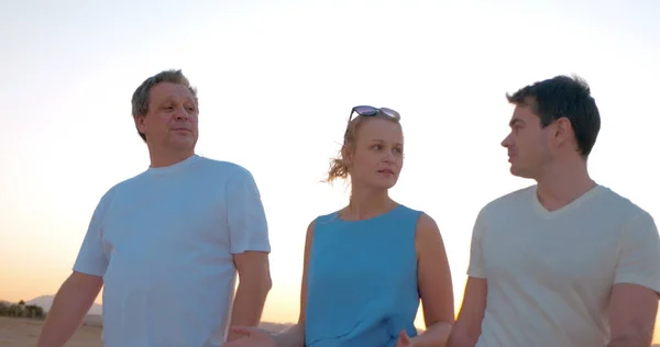 Trois personnes profitant d'une promenade en soirée sur la plage — Photo