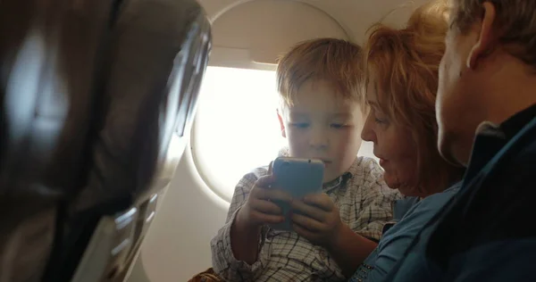 He has a good flight with grandparents and cell phone — Stock Photo, Image