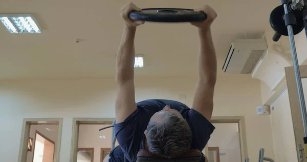 Exercice avec levage de la plaque de poids couché sur le banc — Photo