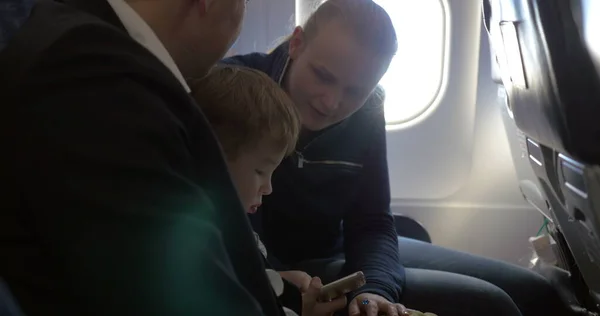 Enfants et jeunes parents voyageant en avion — Photo