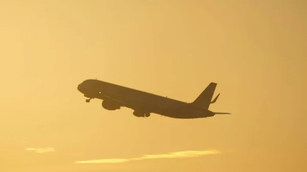 Aereo che vola nel cielo della sera contro il bagliore del sole — Foto Stock