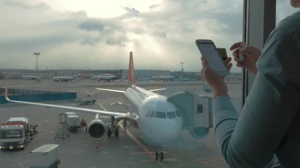 Na visão do aeroporto da mulher que faz o pagamento com cartão bancário usando smartphone e dongle para digitalizar cartão bancário — Fotografia de Stock