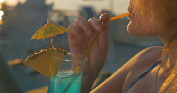 Νεαρή γυναίκα πίνει κοκτέιλ στην παραλία το ηλιοβασίλεμα — Φωτογραφία Αρχείου
